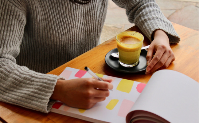 Close-up crop of woman at a table with coffee and notepad with colour swatches - low self esteem- Bolton CBT Emma Yarwood